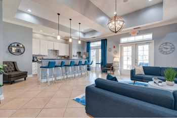 Newly renovated clubhouse with blue couches and chairs and a kitchen with a breakfast bar
